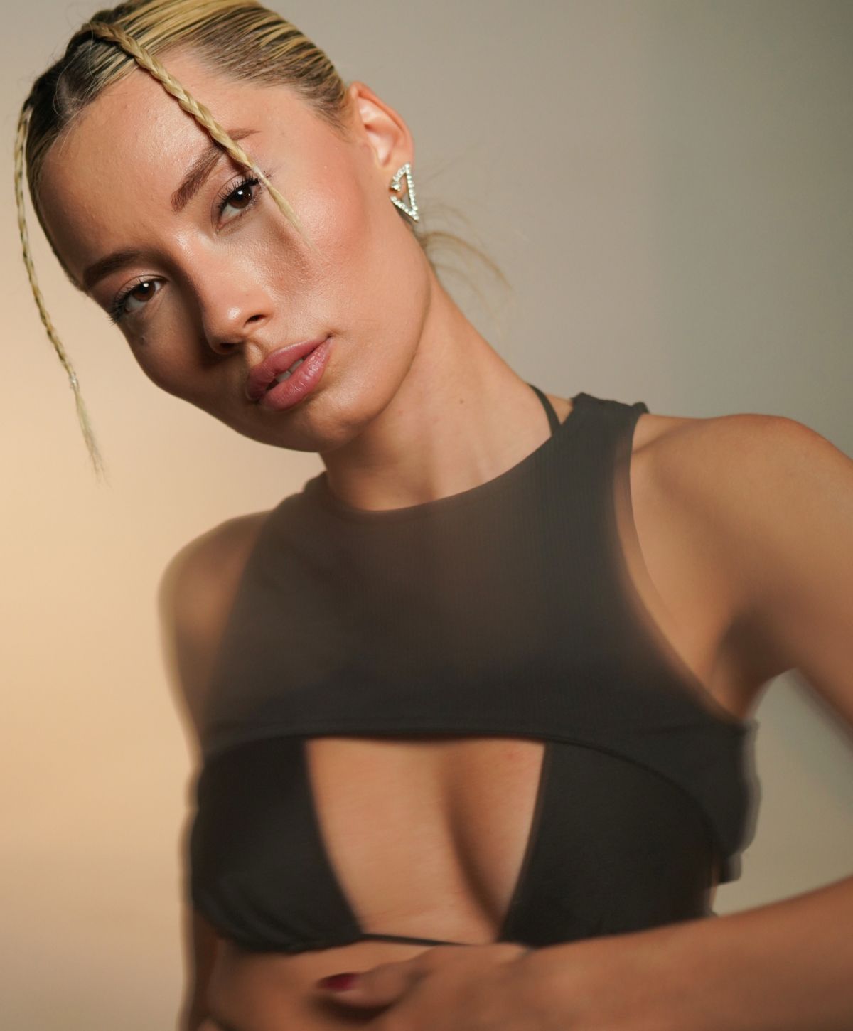 Farmington breast augmentation model posing in stylish black outfit, soft lighting.