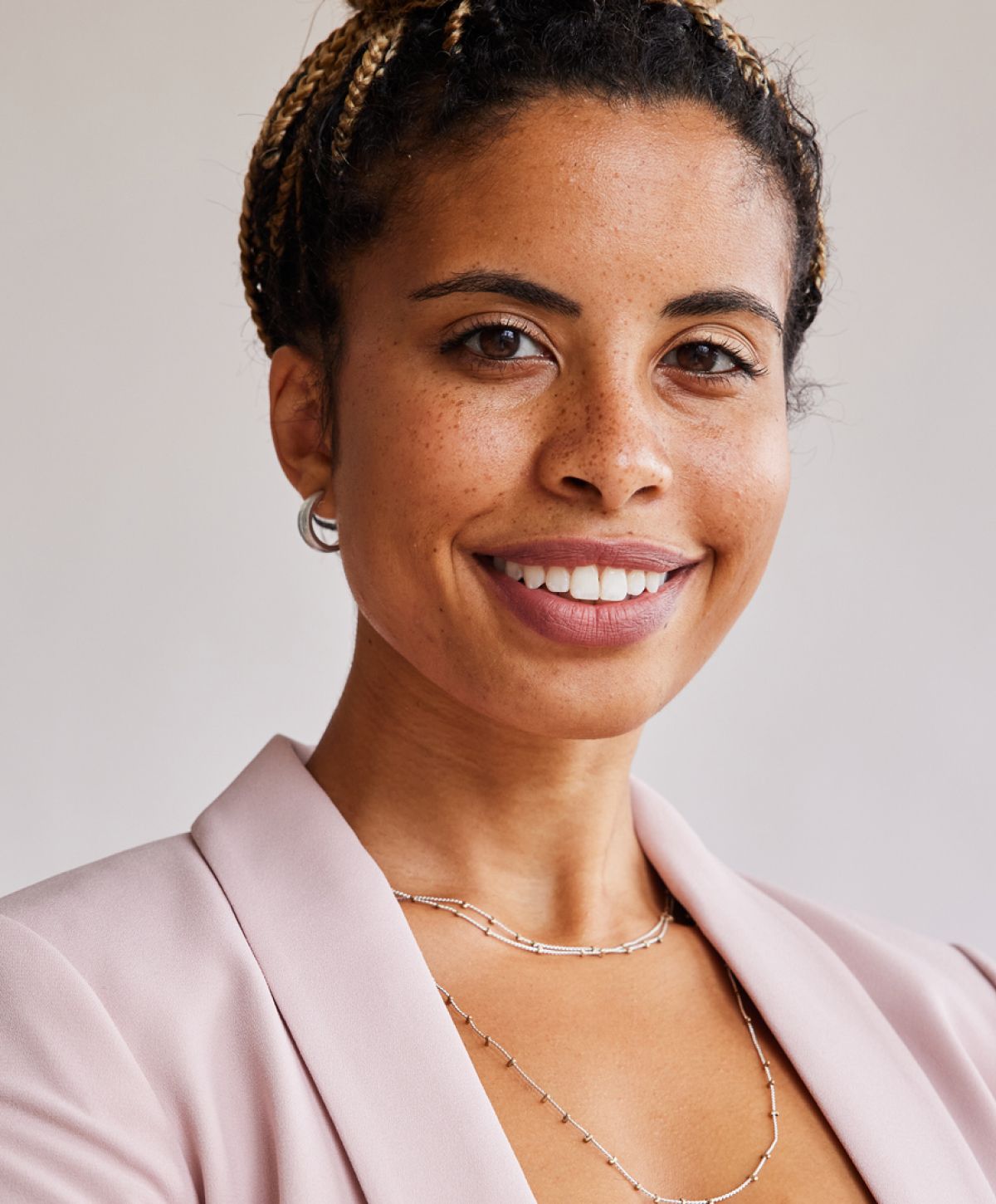 Smiling woman wearing jewelry and a blazer.