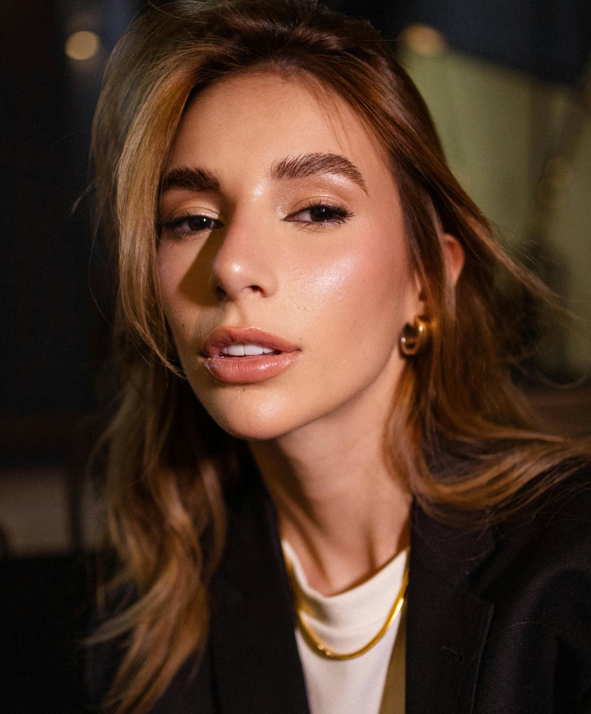 Avon fat transfer model with soft makeup and stylish attire.