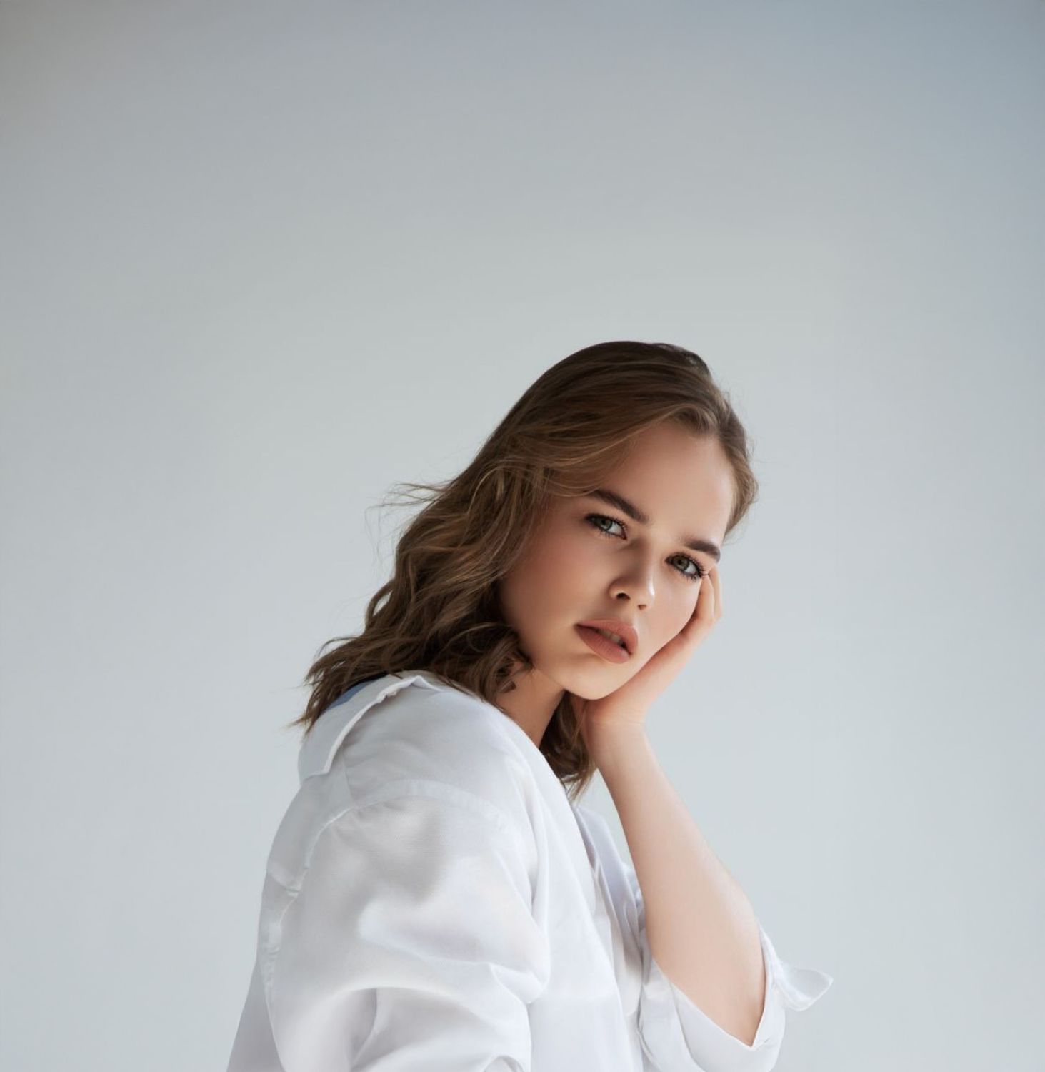 Farmington med spa model in white shirt, thoughtful expression, soft lighting at an Avon med spa.