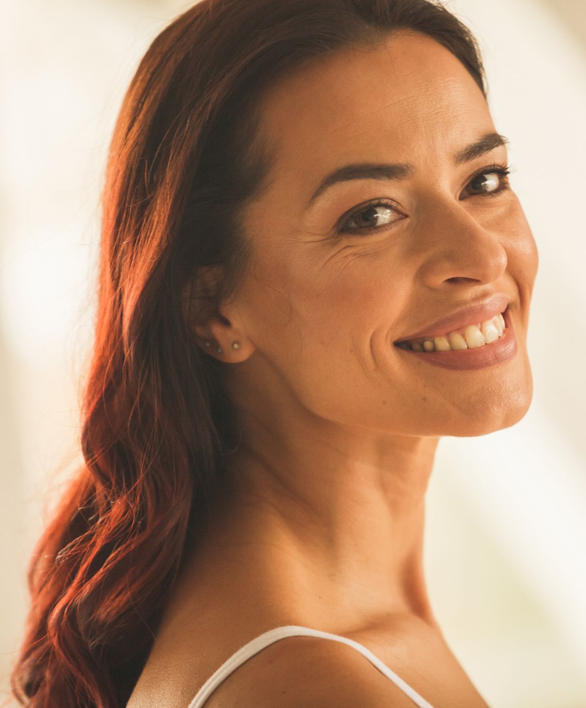 Farmington dermal filler model with long, wavy red hair.