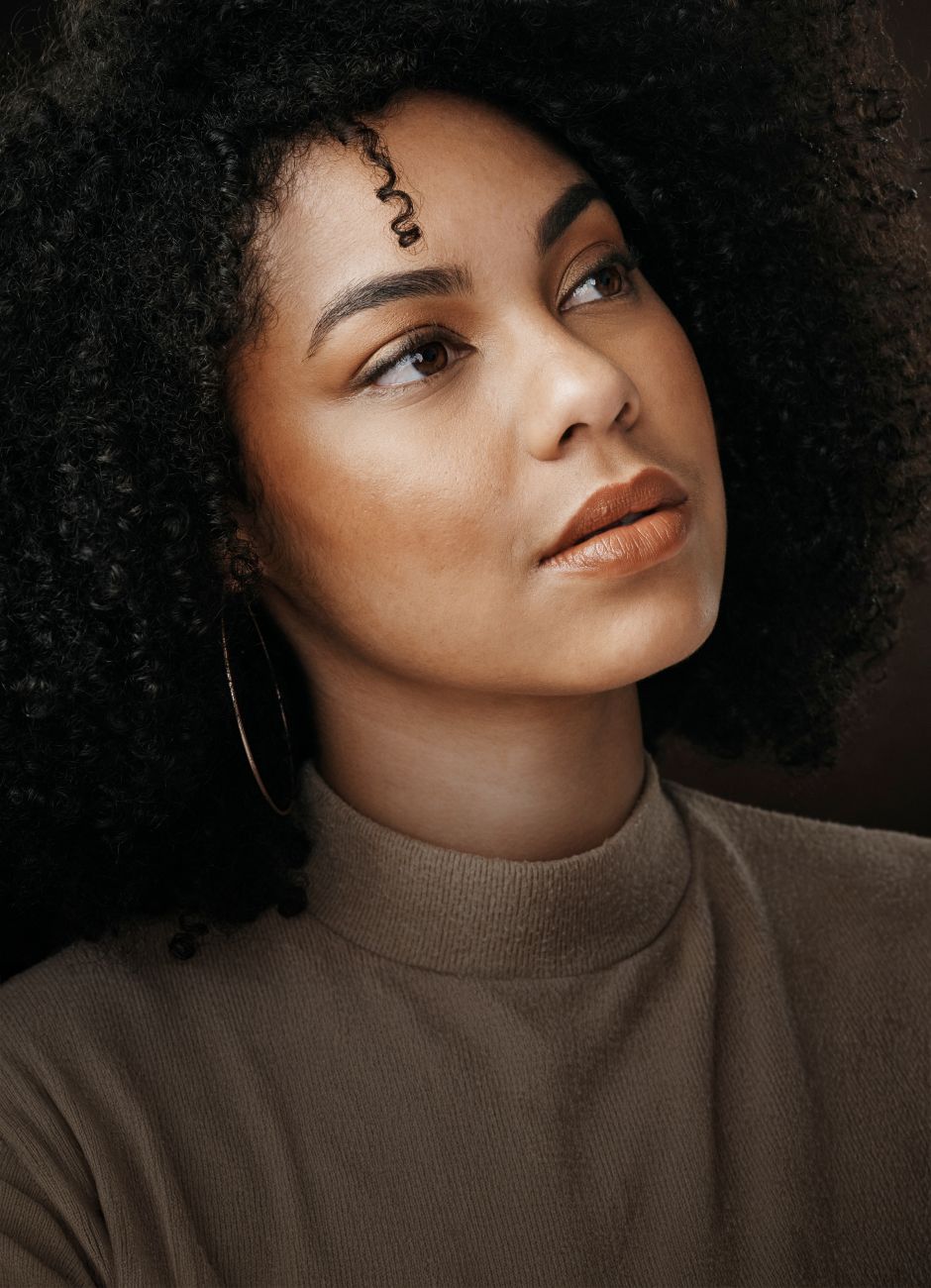 Avon plastic surgery woman with curly hair gazing thoughtfully