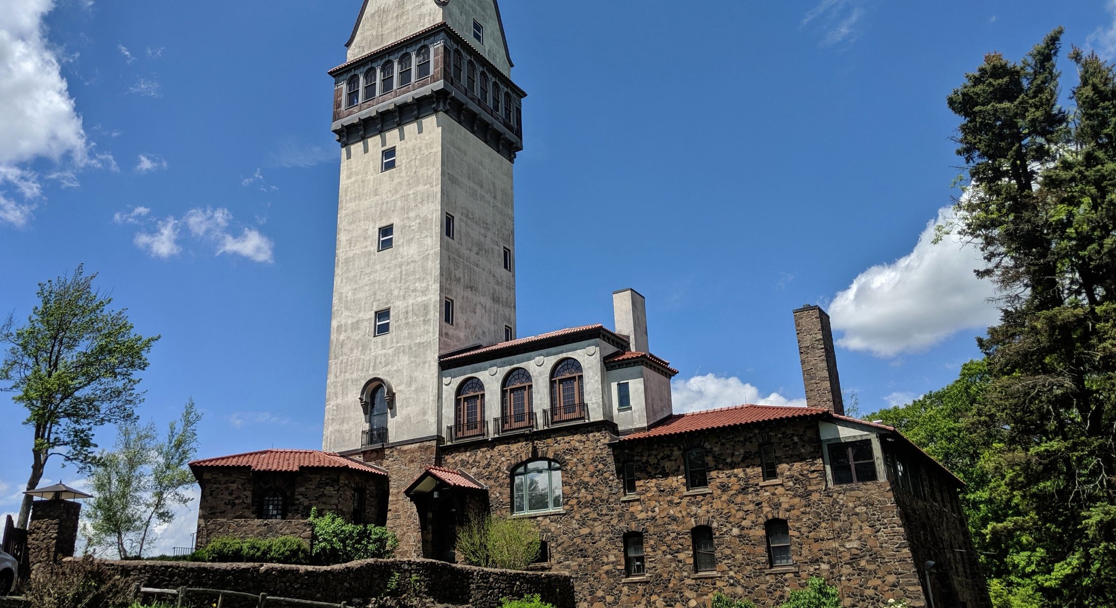 Historic tower surrounded by trees and blue sky.