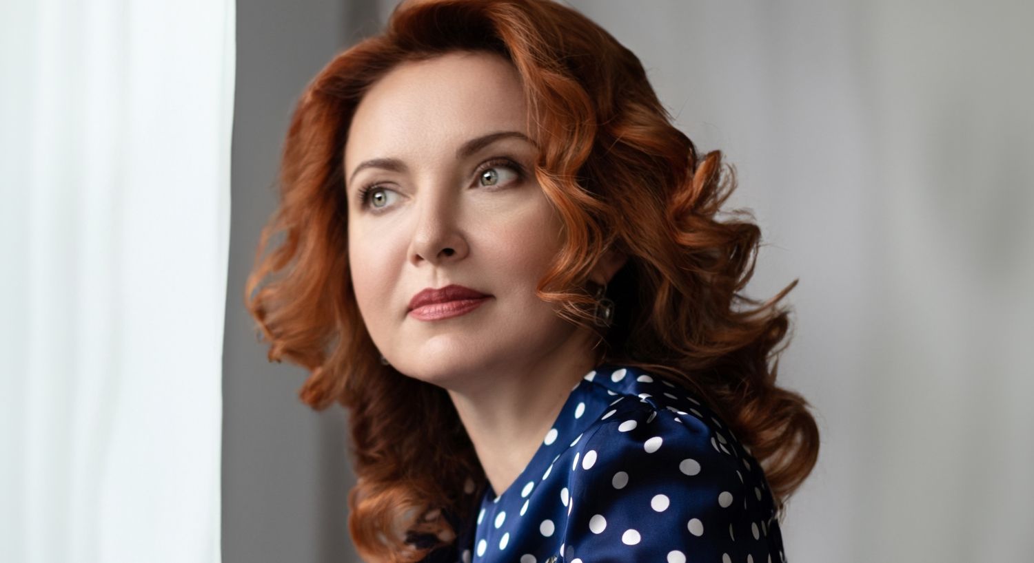 Avon Botox model with curly red hair in polka dot dress.